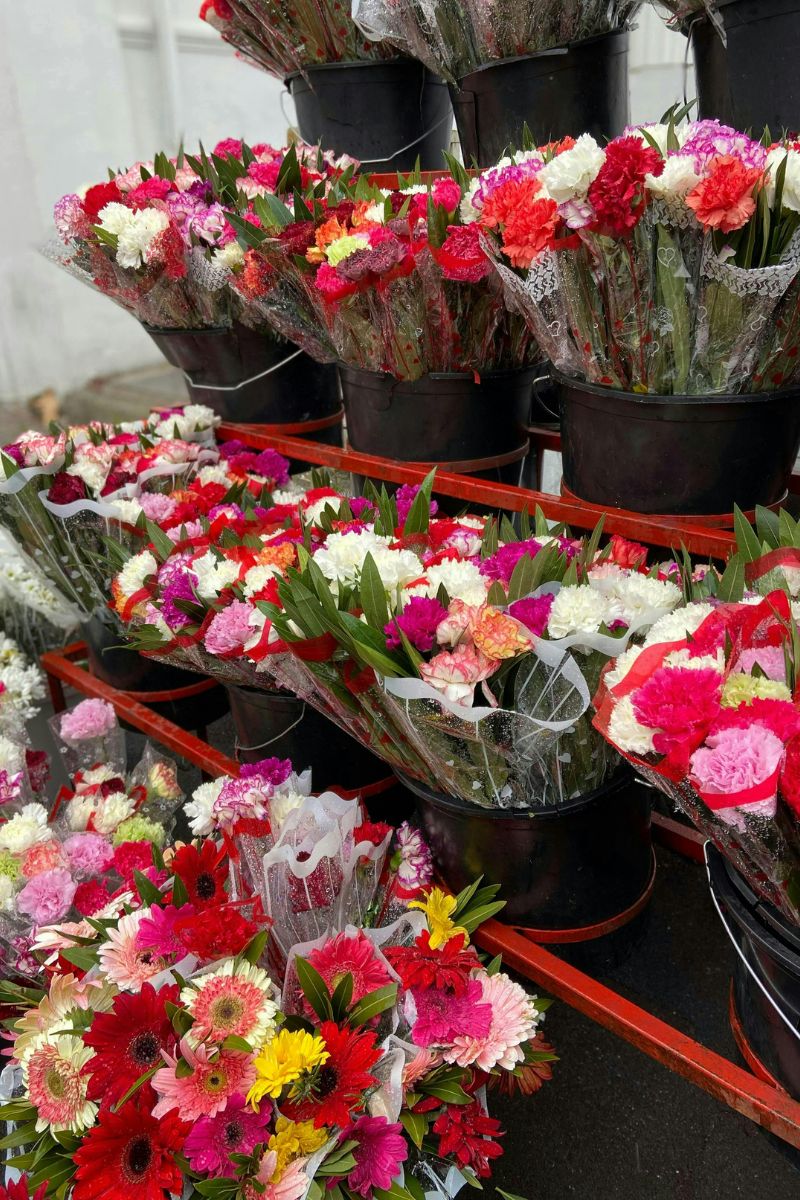 **Florist buckets showcasing bouquets of red, pink, and white carnations ready for retail.**